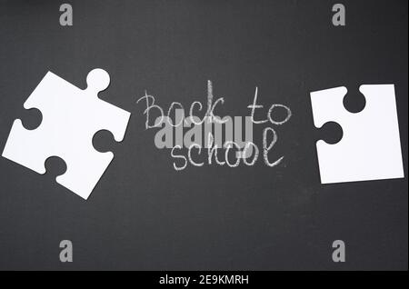 Weiße leere Puzzles und die Aufschrift zurück zur Schule auf schwarz Kreidetafel Stockfoto