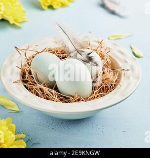 Eier in hellgrüner Schale auf Serviette auf blauem Hintergrund von der Seite. Frühling Frohe Ostern Weihnachtskarte. Quadratisches Bild. Selektiver Fokus. Stockfoto