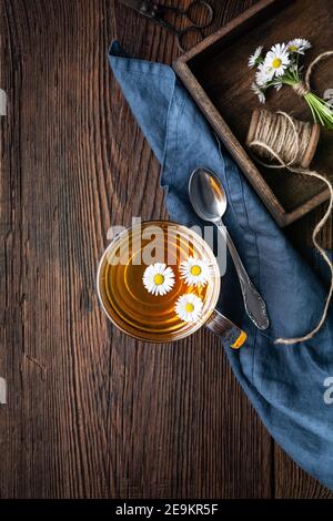 Kräutermedizin für die Gesundheit der Atemwege, eine Tasse Gänseblümchen-Tee auf rustikalem Holzhintergrund Stockfoto