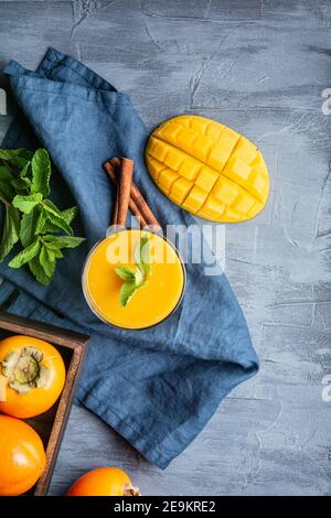 Würziger Mango- und Kaki-Smoothie mit Ingwer und Zimt Das Glas für die Immunität und die Verdauung auf dem rustikalen Holz Hintergrund Stockfoto