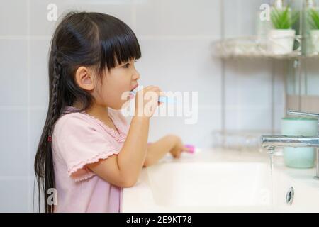 Asiatische niedliche Kind Mädchen oder Kind putzt ihre Zähne mit Zahnbürste im Badezimmer. Zahnhygiene Gesundheitskonzept. Stockfoto