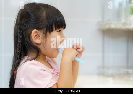 Asiatische niedliche Kind Mädchen oder Kind putzt ihre Zähne mit Zahnbürste im Badezimmer. Zahnhygiene Gesundheitskonzept. Stockfoto