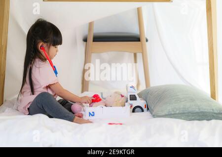 Asiatische nette kleine Mädchen spielen Arzt Rollenmodell während sitzen In einer Decke Fort im Wohnzimmer zu Hause für Perfektes Refugium abseits der anderen Familien Stockfoto