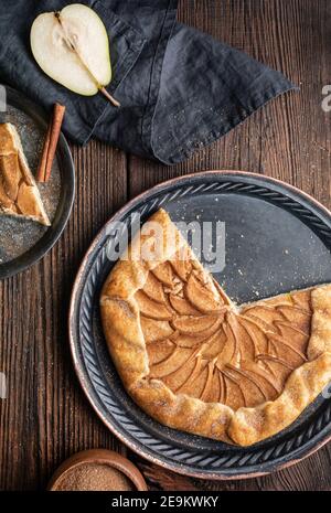 Juicy Birne Galette mit Frischkäse Füllung, bestreut mit Zimtzucker auf rustikalem Holzhintergrund Stockfoto