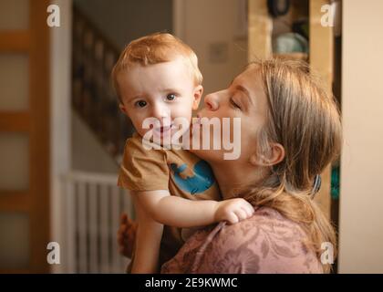 Mutter küsst und umarmt ihr Kind Stockfoto