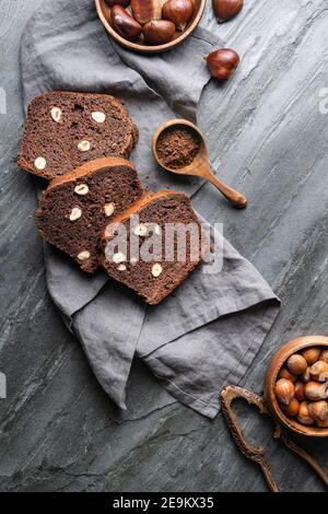Scheiben von Kastanienbrot mit Kakao und Haselnüssen auf Rustikaler Steinhintergrund Stockfoto