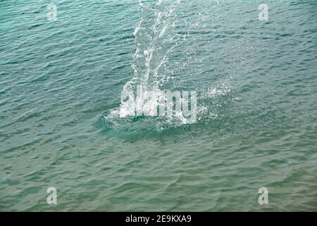 Spritzer, Wellen, Kreise, die von Steinen ins Meer geworfen, Tropfen von frischem, hellem Wasser, Rauschen, Splash. Wellen auf Meer abstrakte Textur Muster BA Stockfoto