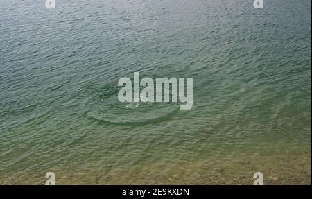 Spritzer, Wellen, Kreise, die von Steinen ins Meer geworfen, Tropfen von frischem, hellem Wasser, Rauschen, Splash. Wellen auf Meer abstrakte Textur Muster BA Stockfoto