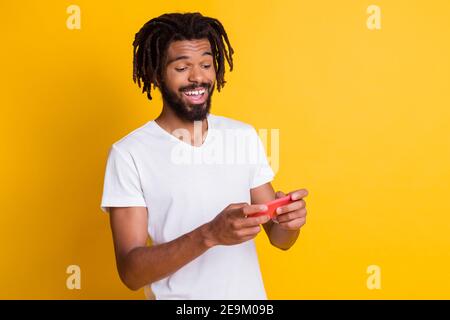 Foto von funky dunkle Haut Kerl halten Telefon spielen neu Videospiel Arcade isoliert gelbe Farbe Hintergrund Stockfoto