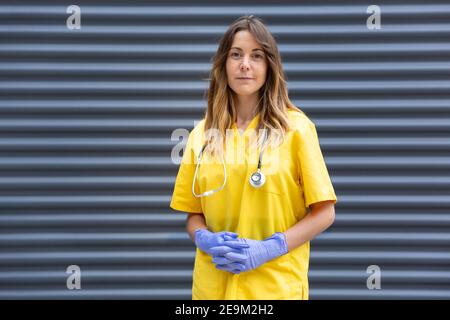 Formales Porträt der kaukasischen Frau Arzt in Uniform, Schutzhandschuhe und Stethoskop. Leerzeichen für Text. Stockfoto