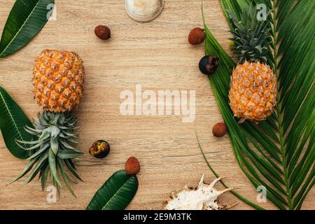 Flach liegend. Tropische Früchte auf braunem Hintergrund mit einem schönen Palmenblatt und Muscheln. Ananas, Mangostan, Litschi. Exotische Früchte für eine gesunde Stockfoto