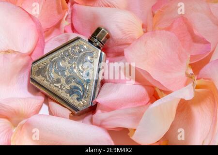 Vintage Silber Parfüm Fläschchen auf Rosenblüten, USA 1940s Stockfoto
