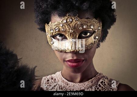 Porträt einer jungen Afrikanerin mit kurzen lockigen Haaren Trägt eine Karnevalsmaske Stockfoto