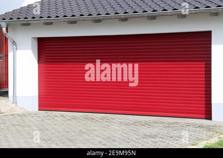 Hochwertiges rotes Garagentor (Sektionaltor) Neben einem Wohnhaus Stockfoto