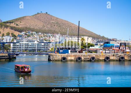 Waterfront - Kapstadt, Südafrika - 03-02-2021 atemberaubende Aussicht auf Red Penny Fähre schwimmend auf dem Wasser, Berg und Brücke überqueren. Stockfoto