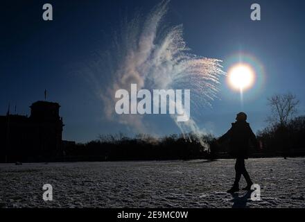 Berlin, Deutschland. Januar 2021, 31st. Auf dem Rasen vor dem Reichstag schleudert ein Mann kochendes Wasser aus einer Flasche in die Luft, die bei den Temperaturen unter dem Nullpunkt sofort friert. Quelle: Paul Zinken/dpa-Zentralbild/ZB/dpa/Alamy Live News Stockfoto