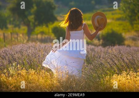 Die Frau in weißem Kleid steht in der Mitte eines Lavendelfeldes in der Türkei. Stockfoto