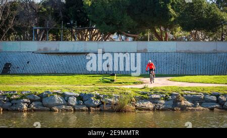 Fuengirola, Malaga, Spanien. Januar 2021. Ein junger Athlet, der im sonnigen Winter morning.depor mit einer Maske im Flusspark Fuengirola Fahrrad fährt Stockfoto