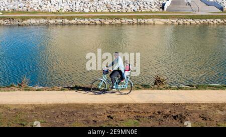 Fuengirola, Malaga, Spanien. Januar 2021. Ein Vater radeln seine Tochter an einem sonnigen Wintermorgen durch den Flusspark in Fuengirola. Stockfoto