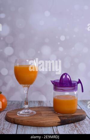 Glas Orangensaft. Glas Entsafter, Orangensaft, Holztisch ganze Orangen mit grünen Blättern hellen Hintergrund Stockfoto