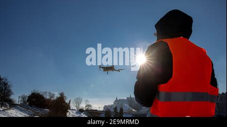 Nahaufnahme des flaying Quadrocopter dron und Pilot Siluette in Sonnenuntergang Licht und blauen Himmel Hintergrund, man fliegt eine Drohne in der Stadt mit einem contr Stockfoto