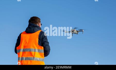 Nahaufnahme des flaying Quadrocopter dron und Pilot Siluette in Sonnenuntergang Licht und blauen Himmel Hintergrund, man fliegt eine Drohne in der Stadt mit einem contr Stockfoto