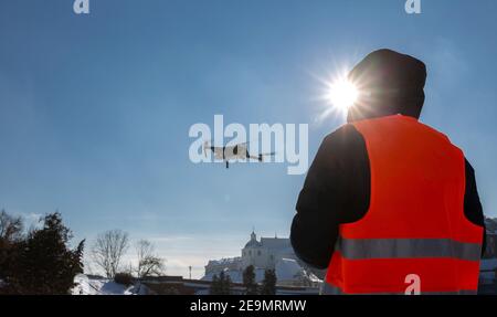 Nahaufnahme des flaying Quadrocopter dron und Pilot Siluette in Sonnenuntergang Licht und blauen Himmel Hintergrund, man fliegt eine Drohne in der Stadt mit einem contr Stockfoto