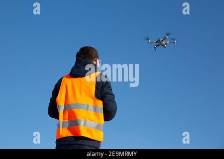 Nahaufnahme des flaying Quadrocopter dron und Pilot Siluette in Sonnenuntergang Licht und blauen Himmel Hintergrund, man fliegt eine Drohne in der Stadt mit einem contr Stockfoto