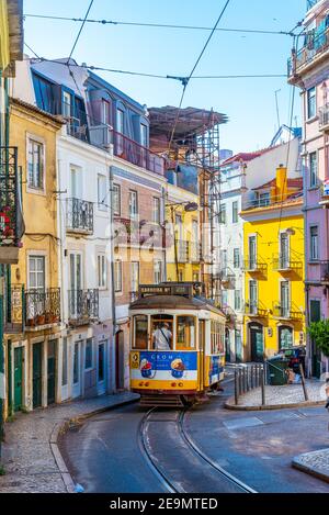 LISSABON, PORTUGAL, 1. JUNI 2019: In Lissabon, Portugal, fährt eine Straßenbahn auf einer schmalen Straße vorbei Stockfoto