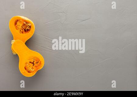 Roher Bio-Butternut-Kürbis oder Gramma in halber Nahaufnahme auf grauem Beton-Hintergrund geschnitten, Draufsicht, kopieren Spase Stockfoto