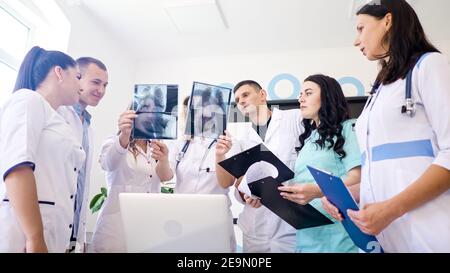 Weibliche Doktorin und junge medizinische Praktikanten in der medizinischen Kleidung Studieren zusammen die Ergebnisse Thorax X-Ray Scan des Patienten. Therapeutin Mittleren Alters Stockfoto