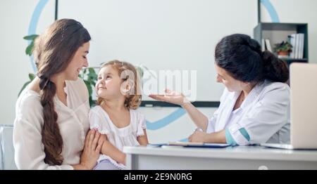 Weibliche Familie Doctor Prüfung und Beratung zu Mutter und ihr Kind. Mutter mit Kind bei Besuch Kinderarzt. Gespräch mit einem Arzt bei der Konsultation Stockfoto