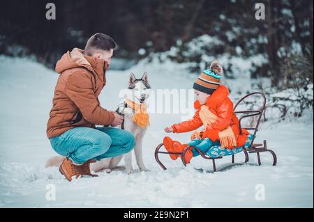 Winter Spiele Papa und Tochter mit Haustier, Husky und seine Besitzer im Winterwald.neu Stockfoto