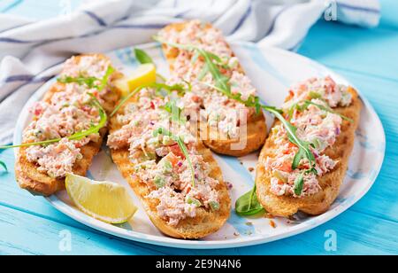 Bruschetta mit gebackenem Lachs. Tapas. Sandwich mit Lachssalsa, Feta-Käse, Avocado, Tomaten und roten Zwiebeln. Toast mit Riyet Lachs. Stockfoto