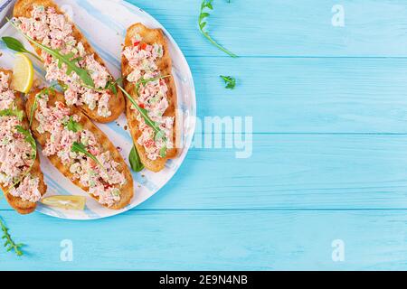 Bruschetta mit gebackenem Lachs. Tapas. Sandwich mit Lachssalsa, Feta-Käse, Avocado, Tomaten und roten Zwiebeln. Toast mit Riyet Lachs. Draufsicht, Stockfoto