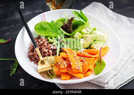 Vegane Mahlzeiten, Mittagessen. Buddha-Schale mit Quinoa, gebratenem Kürbis, Avocado und grünen Kräutern. Vegetarische, gesunde Ernährung Konzept. Stockfoto