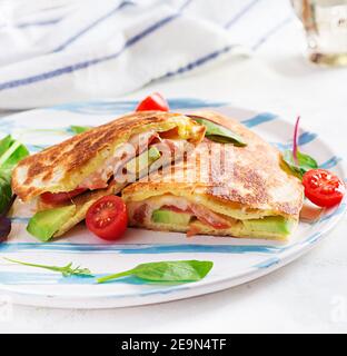 Leckeres Frühstück mit Quesadilla und Eiern. Mexikanische Küche. Trendgerichte mit Omelette, Käse, Tomaten, Avocado. Einfaches und leichtes Mittagessen. Stockfoto