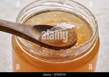 Abgekühlte geriebene Rinderknochenbrühe auf einem Löffel darüber Ein Glas Stockfoto