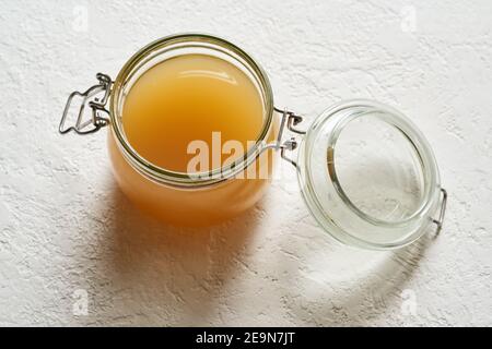 Hausgemachte Rinderknochenbrühe in einem Glas auf einem Weißer Hintergrund Stockfoto