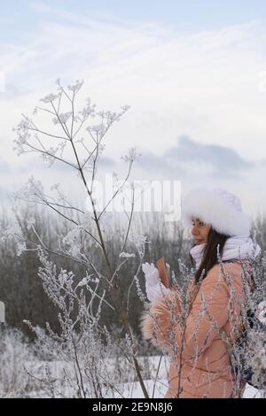 Mädchen auf einem Spaziergang im Winter Park. Fotografien Pflanzen bedeckt mit Frost und Schnee. Stockfoto