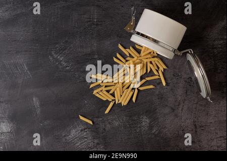 Detail eines weißen Keramikglases mit Deckel mit Makkaroni Innen auf dunklem Hintergrund Stockfoto