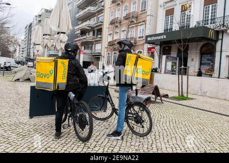 Ein paar Glovo Kuriere sahen in einem Restaurant in Lissabon auf Online-Bestellungen warten.die Pandemie hat die Anzahl der Kuriere ausgelöst, die auf den Plattformen für die Lebensmittelzustellung arbeiten. Im Zentrum von Lissabon, viele Menschen wählen, um Lieferungen auf Fahrräder und Elektro-Scooter unter Nutzung des Netzes von Fahrradwegen. Stockfoto