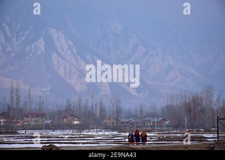 Pendler gehen entlang der Straße mit schneebedeckten Bergen im Hintergrund während eines Winterabends in Srinagar.Wetter über die Stadt Srinagar hat sich verbessert, nachdem Kaschmir frischen Schneefall erhielt. Die Mindesttemperatur blieb über dem Gefrierpunkt in der Stadt Srinagar, da das Wetterbüro das trockene Wetter für die nächsten sieben Tage prognostizierte. Stockfoto