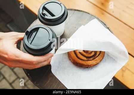 Essen zum Mitnehmen - Kaffee und ein Brötchen auf einem Straßentisch. Stockfoto