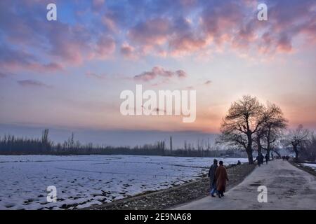 Pendler gehen entlang der Straße während des Sonnenuntergangs in Srinagar.Wetter über der Srinagar Stadt hat sich verbessert, nachdem Kaschmir frischen Schneefall erhielt. Die Mindesttemperatur blieb über dem Gefrierpunkt in der Stadt Srinagar, da das Wetterbüro das trockene Wetter für die nächsten sieben Tage prognostizierte. Stockfoto