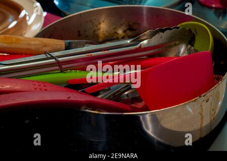 Schmutziges, gebrautes Geschirr und Besteck stapelten sich auf der Theke in der Topfschale und warteten darauf, nach dem Kochen einer großen Mahlzeit für die Familie gereinigt zu werden. Stockfoto