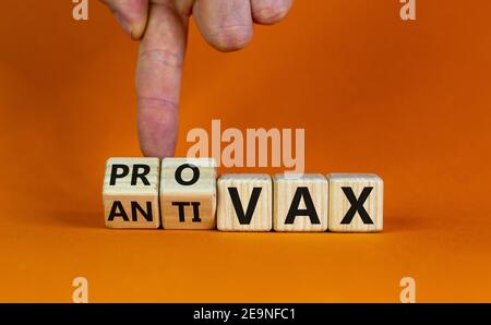 Pro-vax- oder Anti-vax-Symbol. Der Arzt dreht einen Würfel, ändert die Worte „Anti-vax“ in „Pro-vax“. Schöner orangefarbener Hintergrund. Speicherplatz kopieren. Business, medizinische Kov Stockfoto