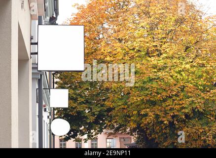 Drei leere Wandschilder im Freien, die in der Herbststadt hängen, leere Geschäftsschilder mit Platz zum Kopieren, um Text oder Logo hinzuzufügen Stockfoto