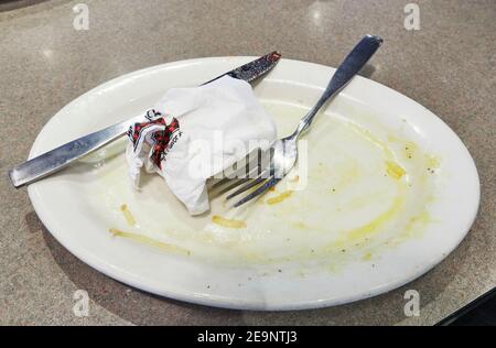 Dreckiger leerer Teller mit Messer und Gabel nach dem Frühstück mit Eiern in einem Restaurant. Stockfoto