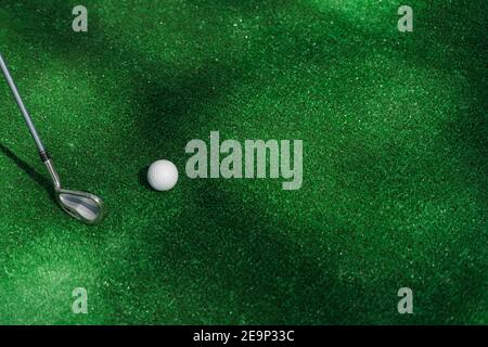 Golf Sport Spiel mit Niblick und weißen Ball auf dem grünen Gras. Spielen im Minigolf. Leerer Platz für Werbung rechts. Stockfoto
